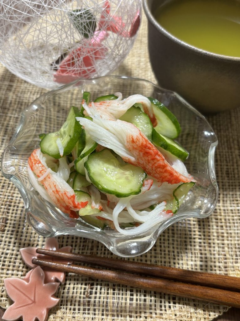 Refreshing Japanese Cucumber and Crab Stick Sunomono served in a bowl, garnished and ready to enjoy at home.シャキシャキきゅうりとカニカマの酢の物、器に盛り付けられた完成形の日本の家庭料理。