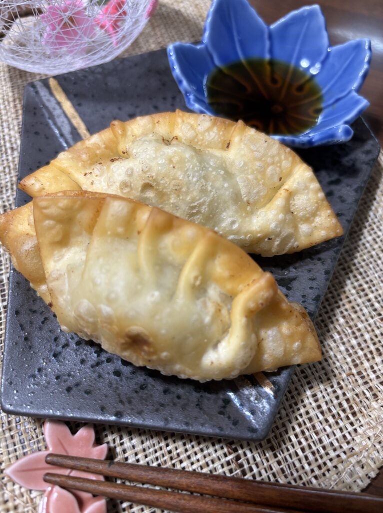 Crispy fried gyoza (Japanese dumplings) on a plate, golden brown and juicy inside, a popular Japanese home cooking dishこんがり揚がった揚げ餃子の完成写真。外はカリッと中はジューシーな日本の家庭料理